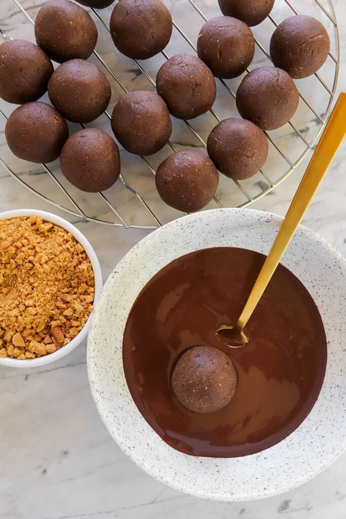 Gingerbread balls getting coated in chocolate.
