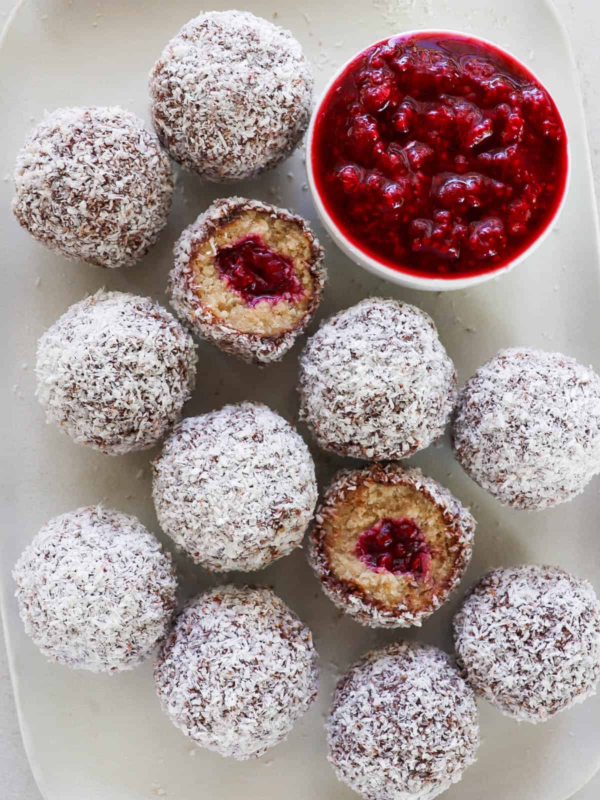 Plate of Lamington balls with mashed raspberries on side.