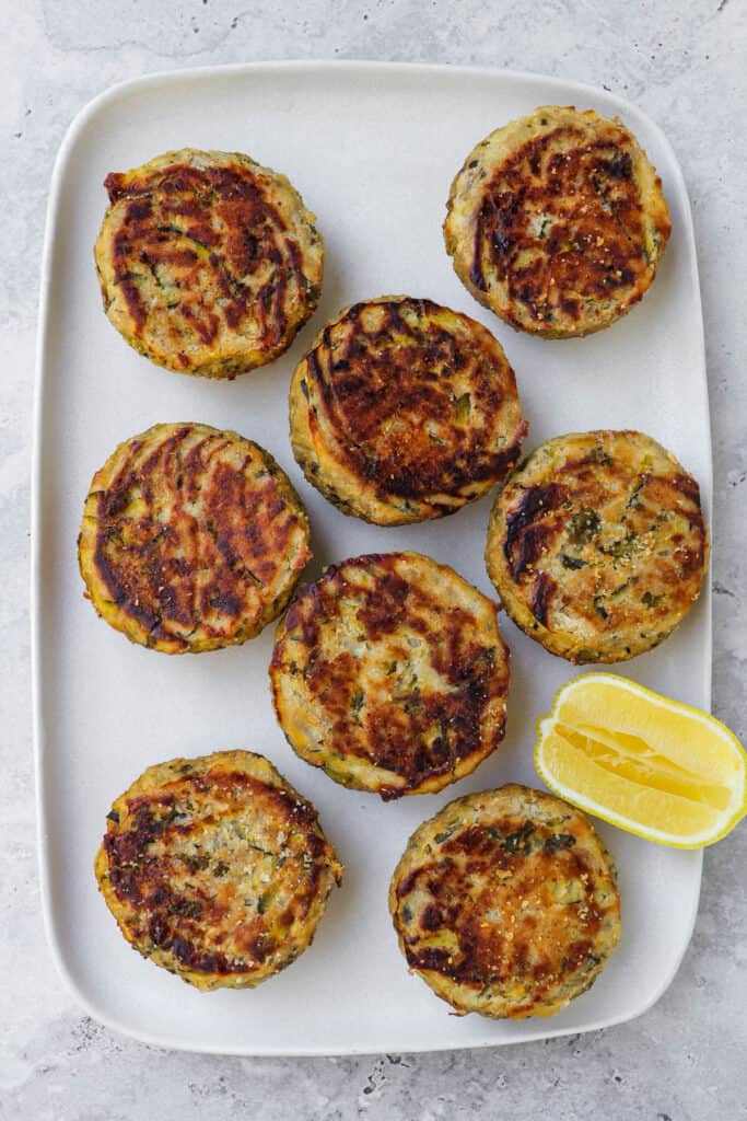 Baked tuna cakes on plate with lemon wedge.