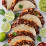 Baked sweet potato mushroom tacos with limes, guacamole and salsa on side for decoration.
