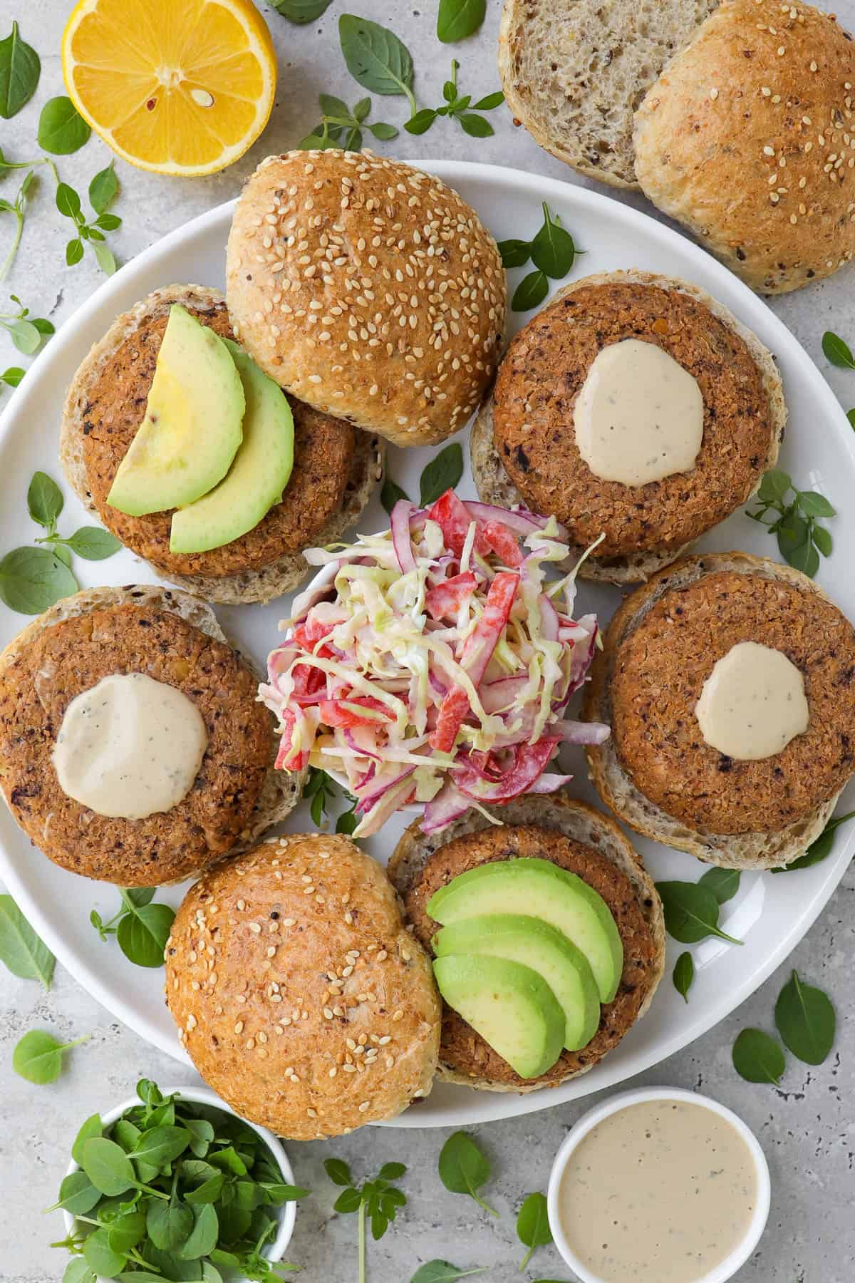 Patties on plate in burger buns with slaw and avocado.