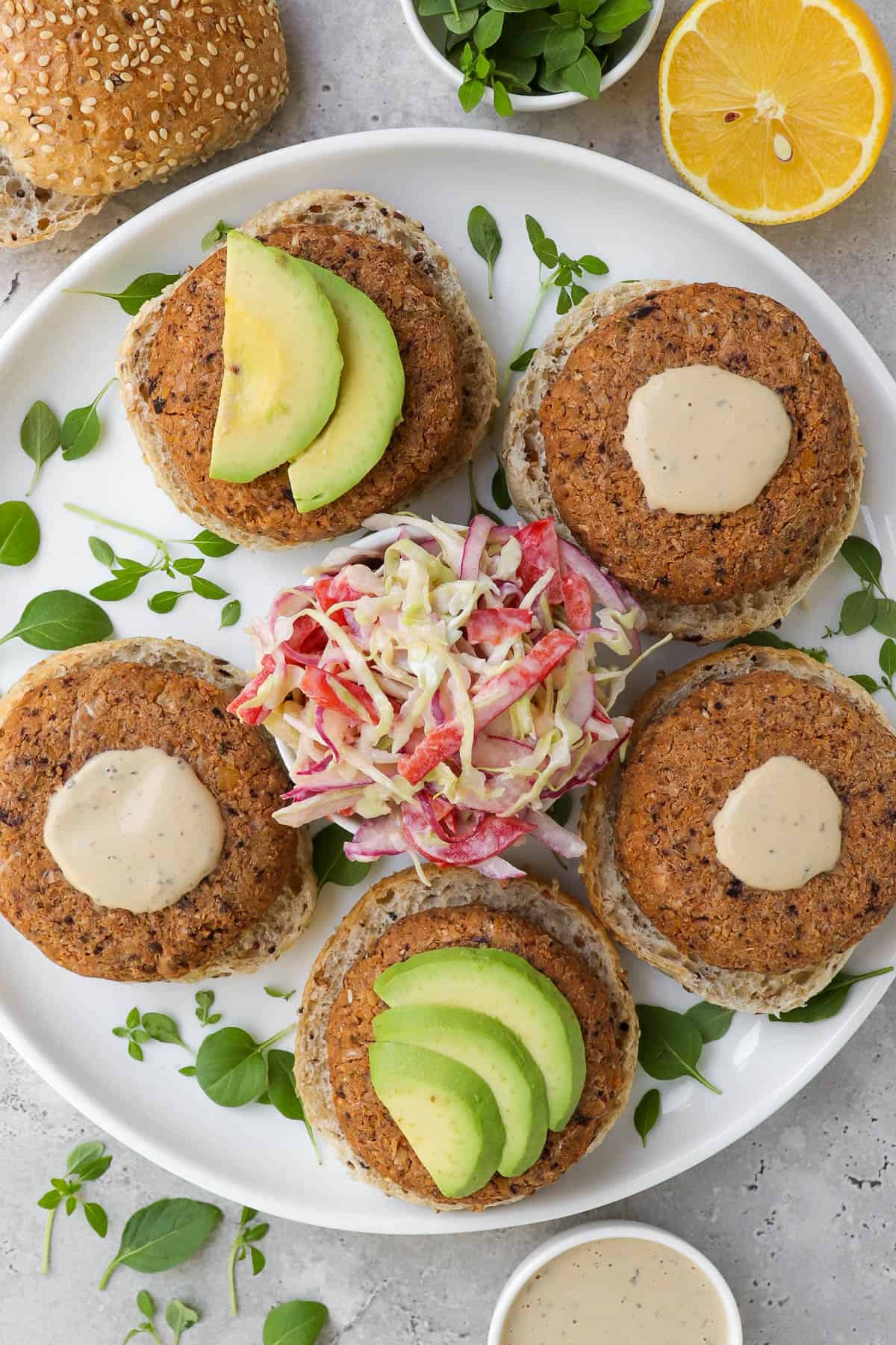Over view of patties on plate in burger buns with slaw and avocado.