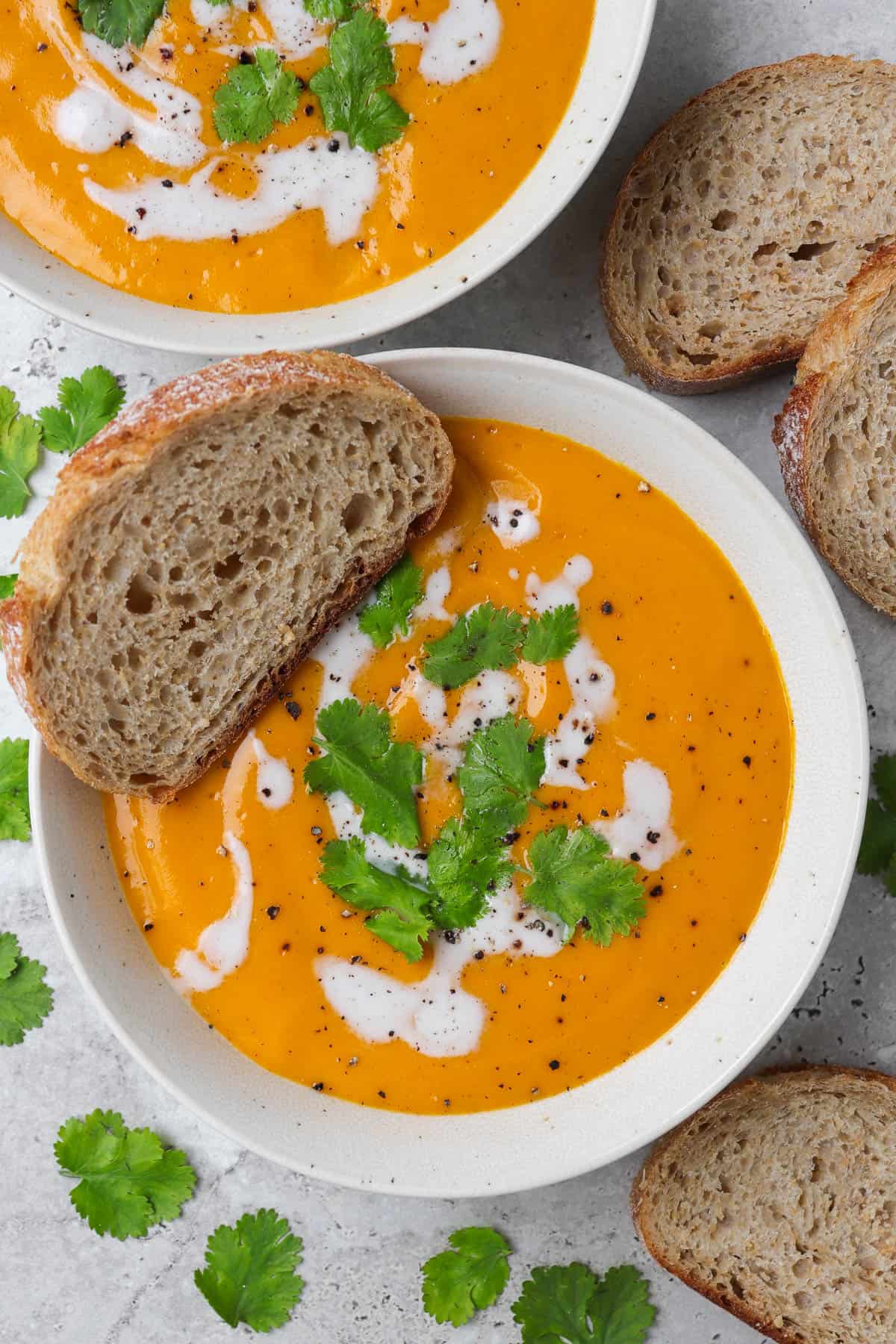 Carrot swede soup in a bowl with sourdough dunked in.