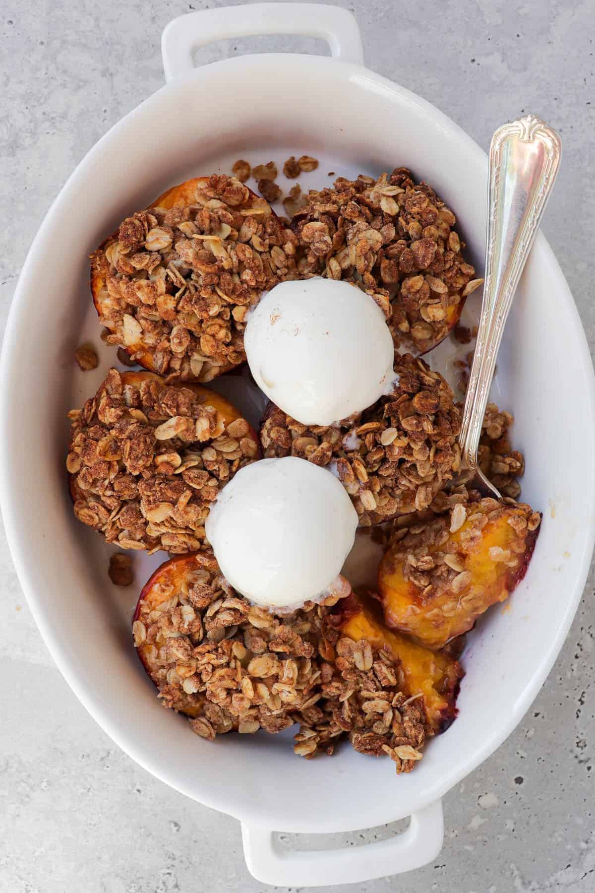 Air fryer peaches in dish with ice cream.