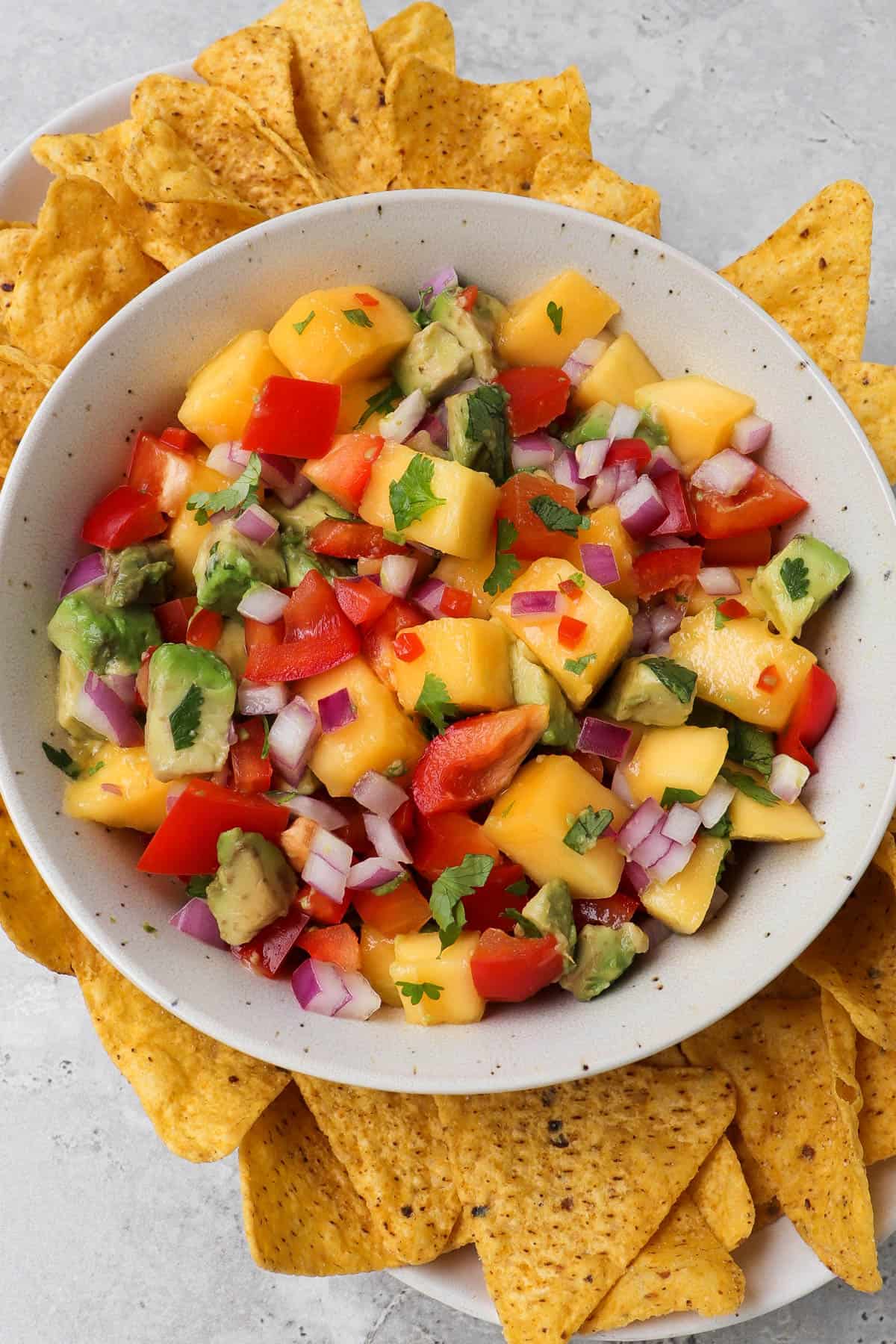 Side shot of mango salsa in a bowl with corn chips.