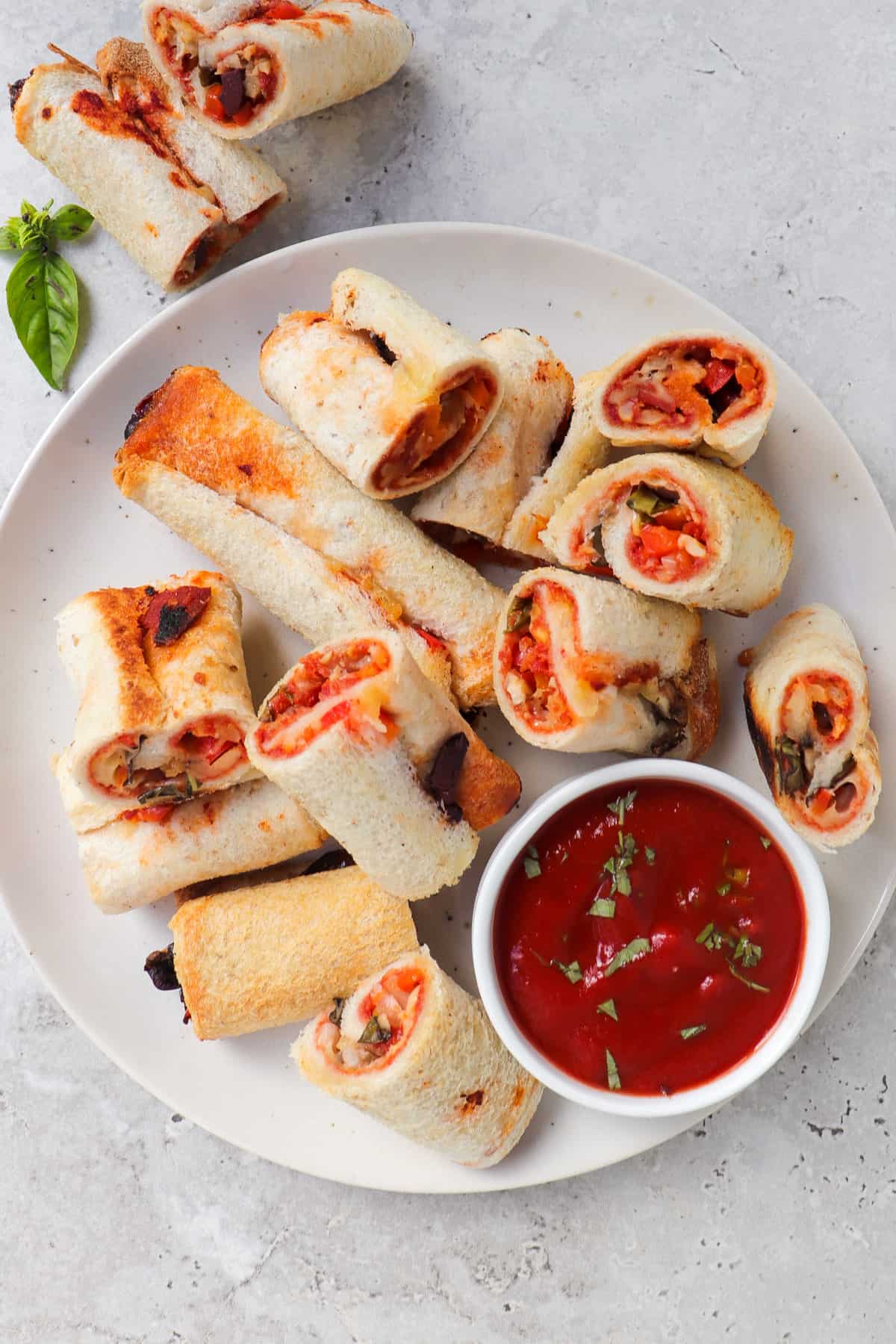 Cooked gluten free pizza rolls on a plate with tomato sauce