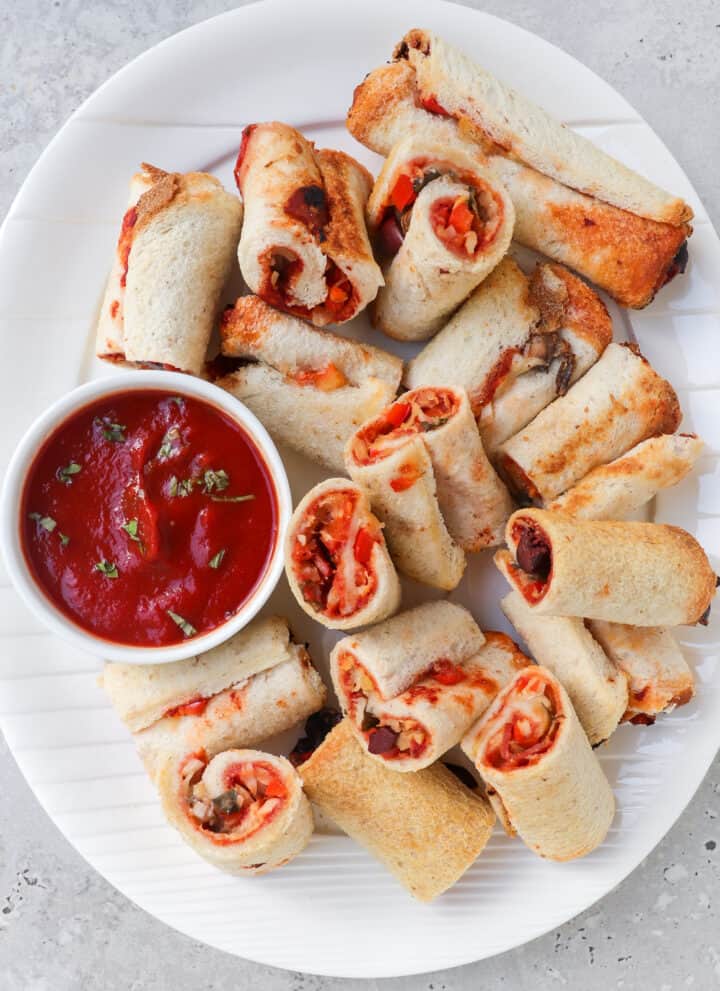 Cut up gluten free pizza rolls on a plate with tomato