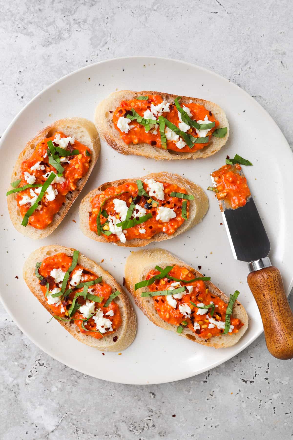 Crostini with dip topped with feta, basil and chili flakes.