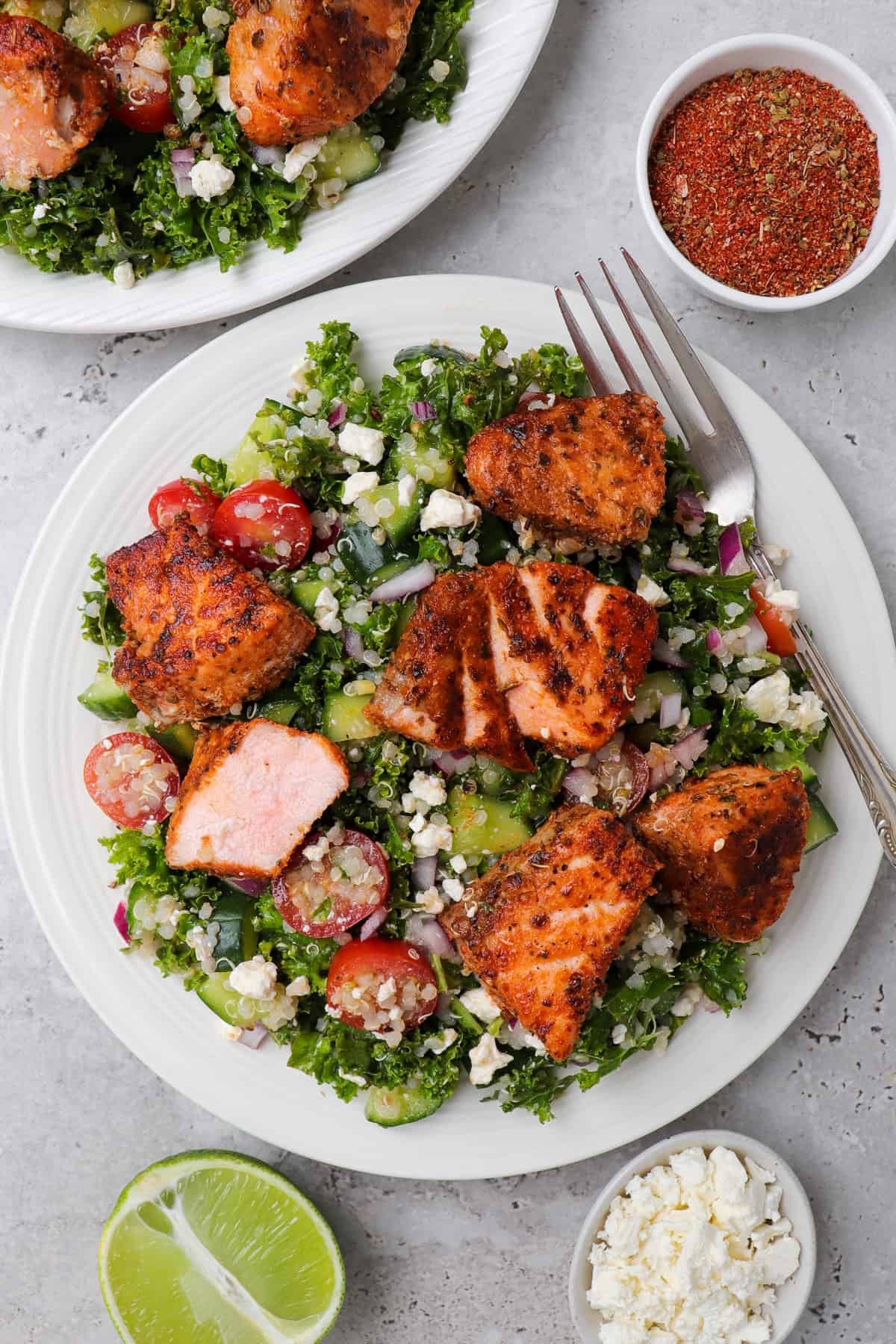 Kale and quinoa salad on a plate with cajun salmon on top.