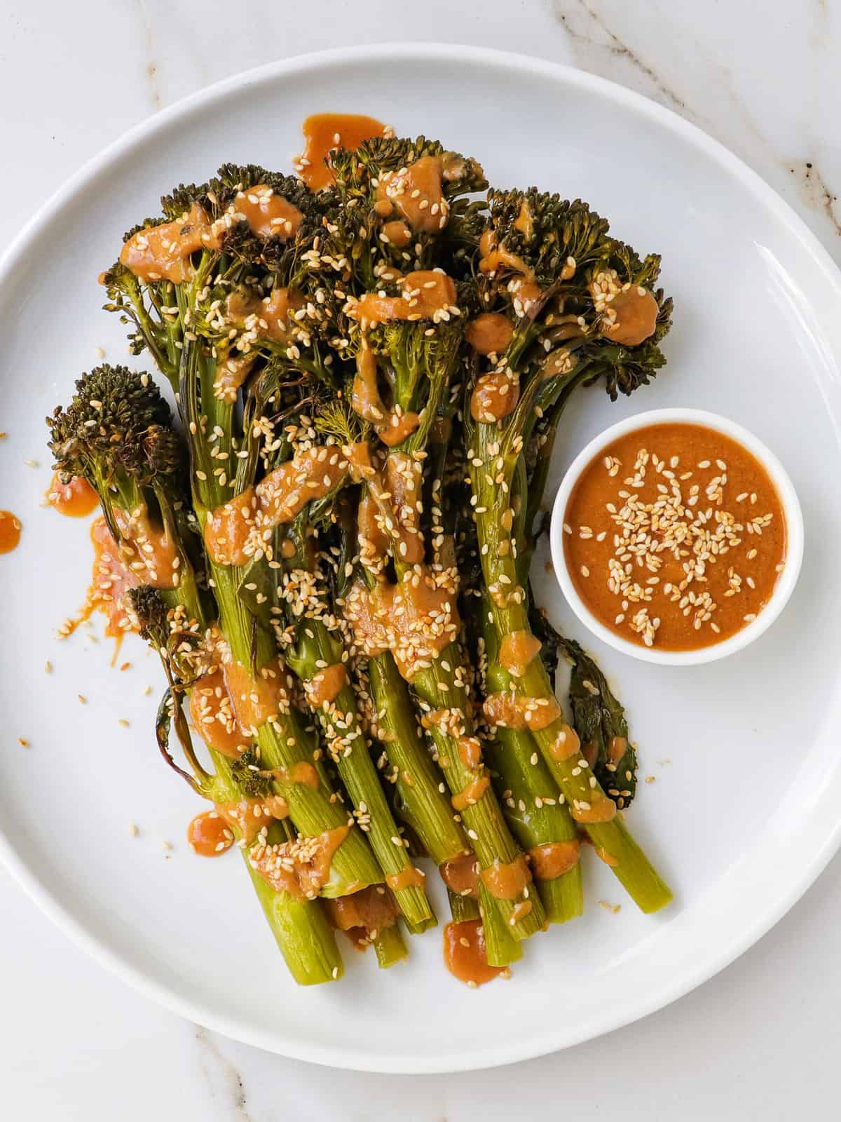 Tenderstem broccoli on a plate with miso sauce drizzled on top.
