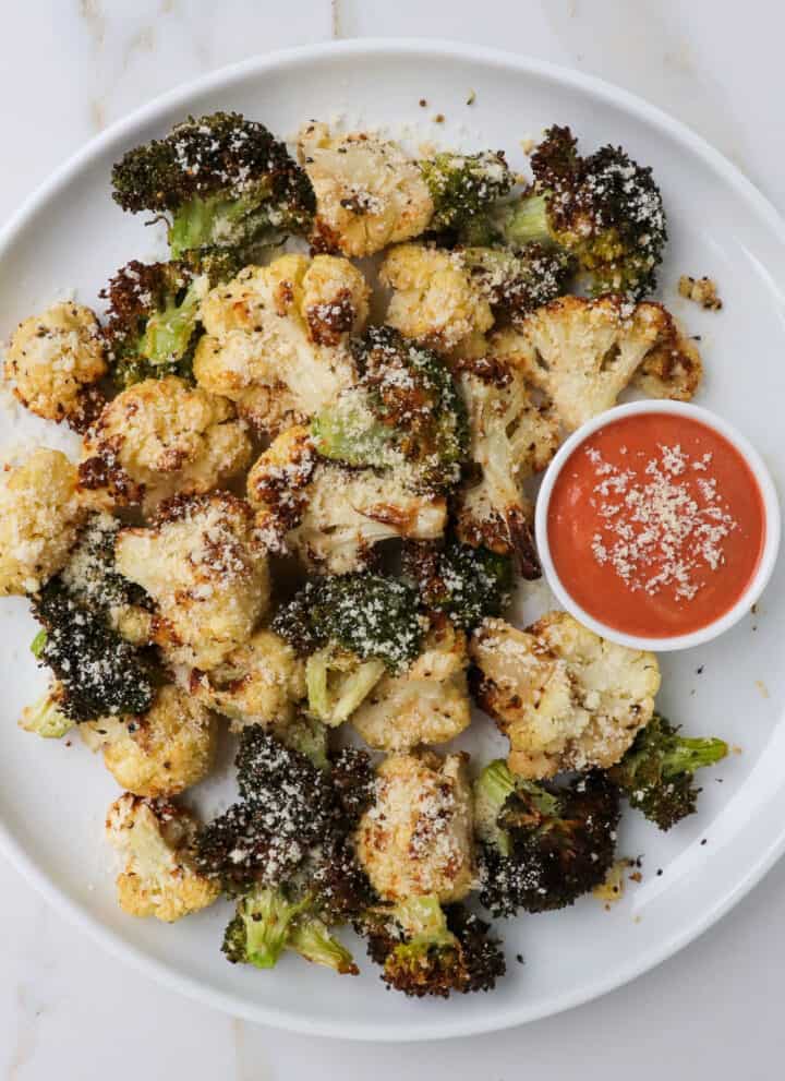 Crispy cauliflower and broccoli on a plate with red sauce.