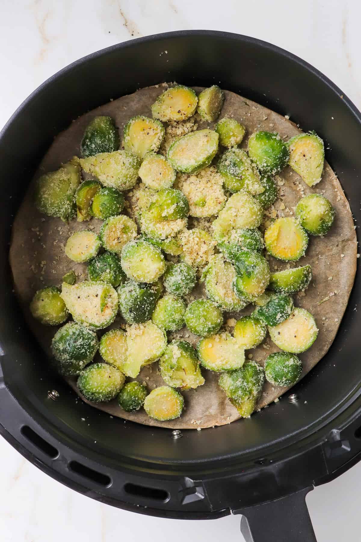 Parmesan crusted brussles sprouts in air fryer basket.