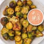Air fryer roasted Brussels sprouts on a plate with creamy tomato sauce.