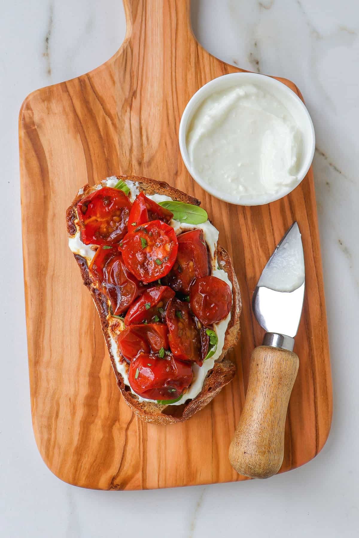 Slice of toast with tomatoes on wooden board.