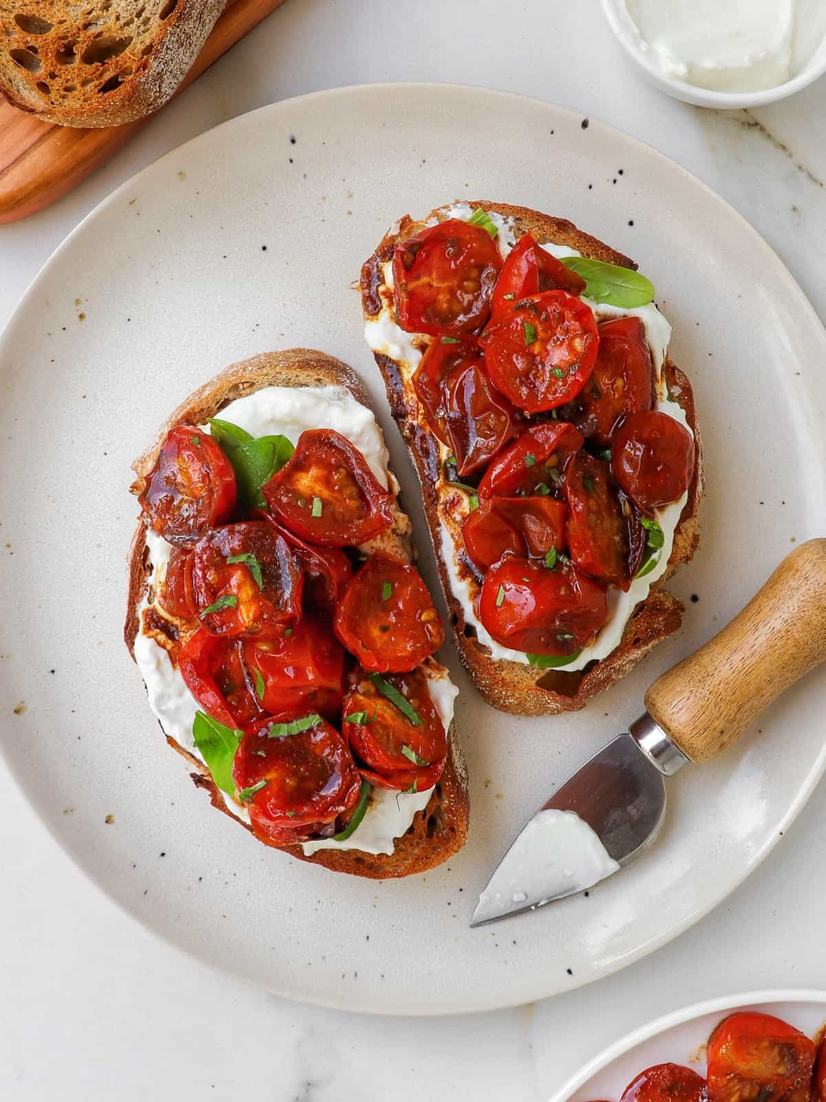 Tomato toasts on plate with knife.