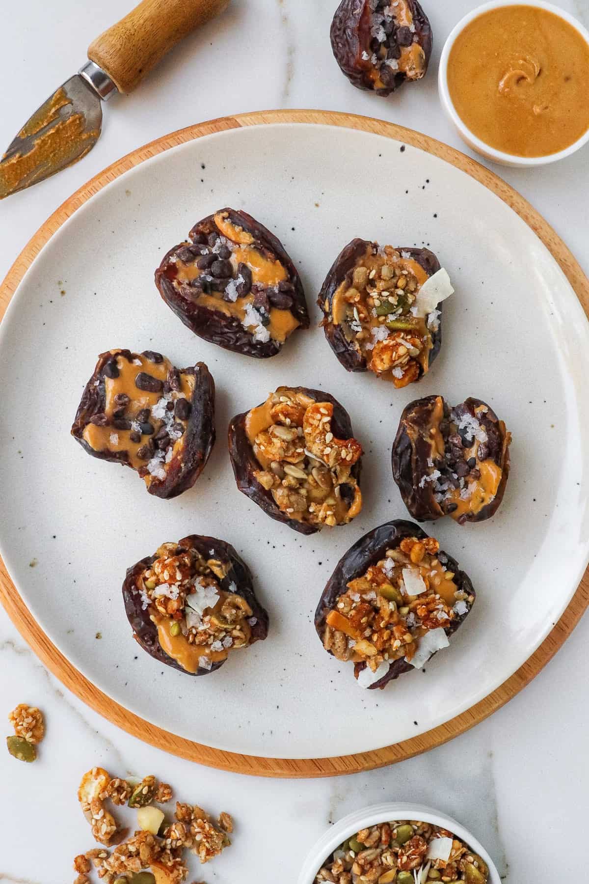 Peanut butter stuffed dates with granola and cacao nibs on a plate.