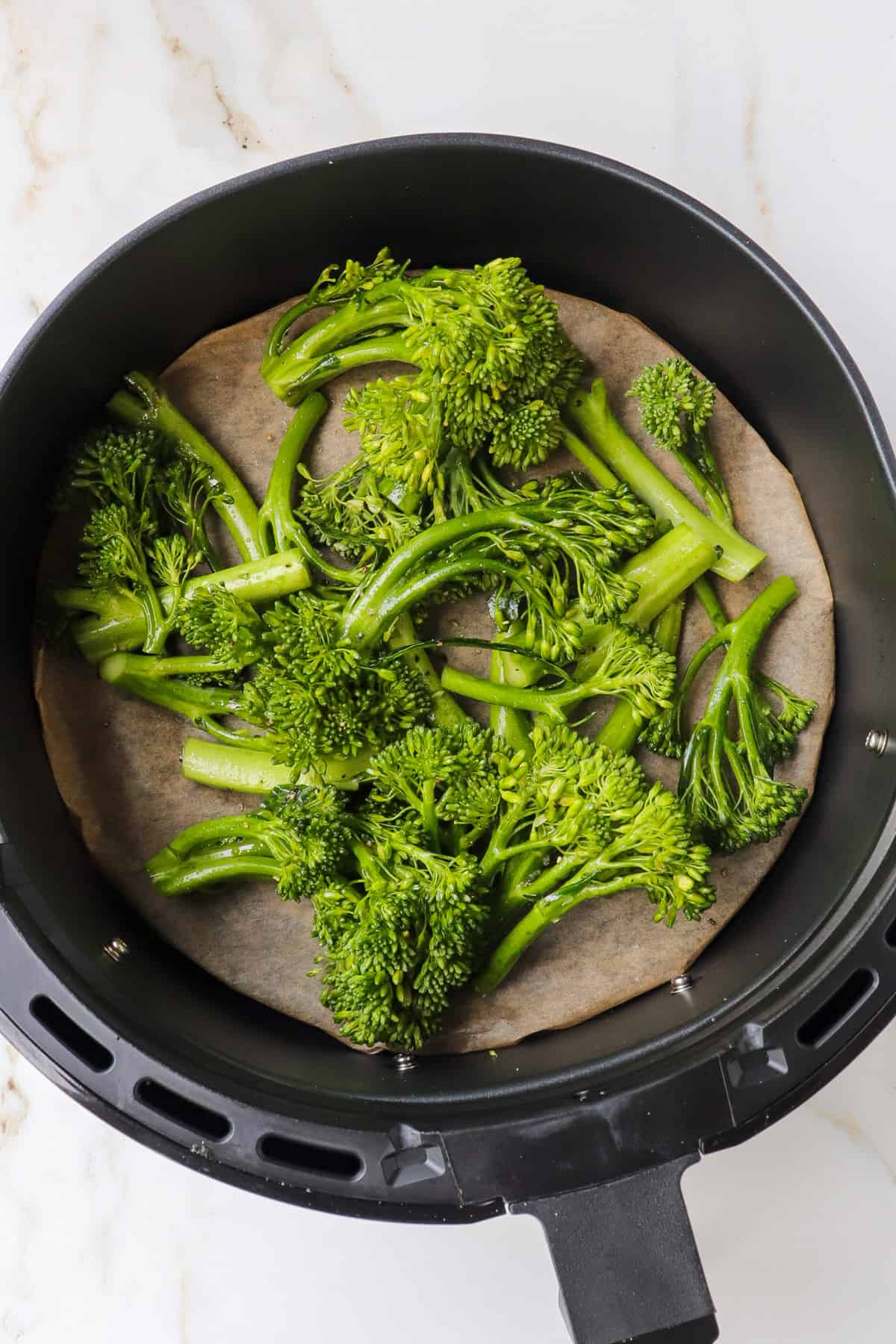 Broccolini in air fryer basket.