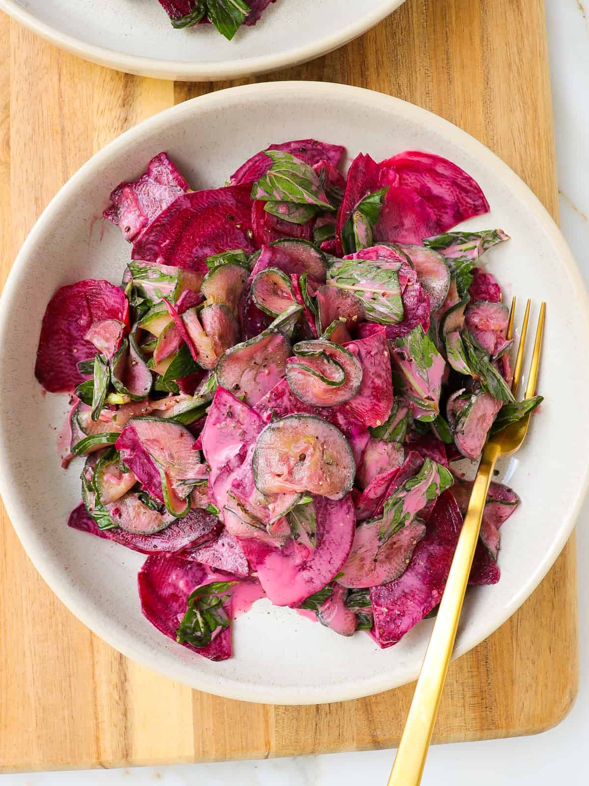 Cucumber beetroot salad in a bowl on a wooden board.