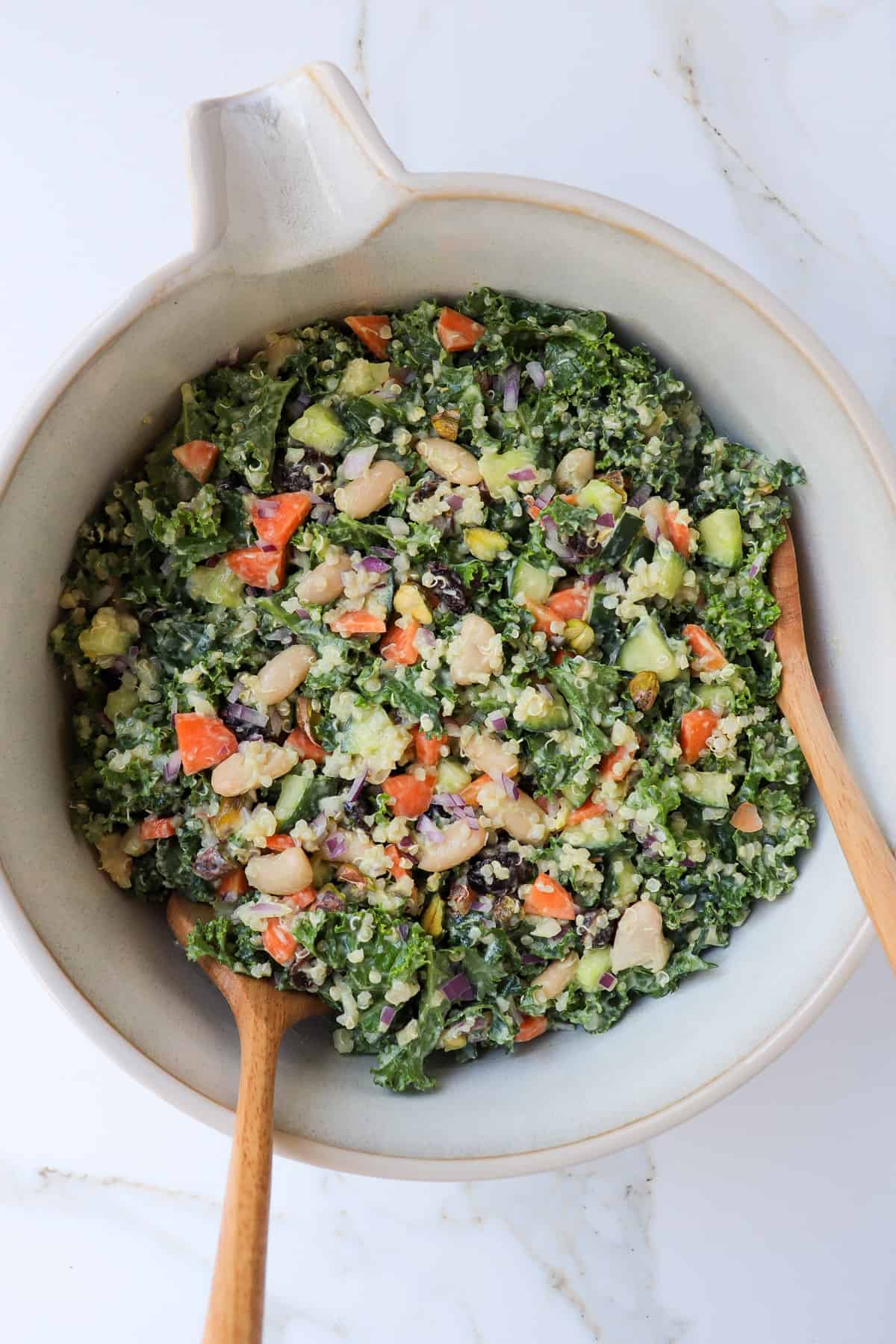 Kale salad in a bowl with mixing spoons.