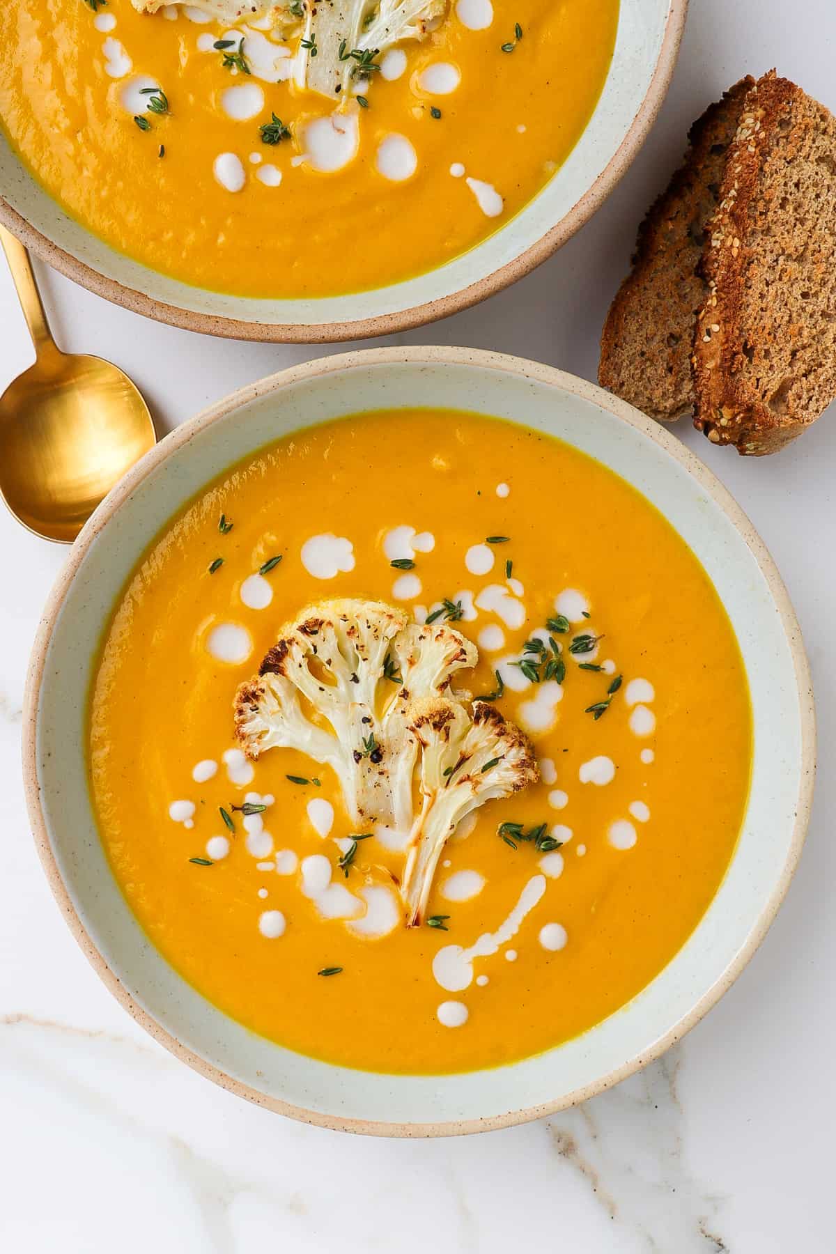 Pumpkin soup served in a bowl with roasted cauliflower on top.