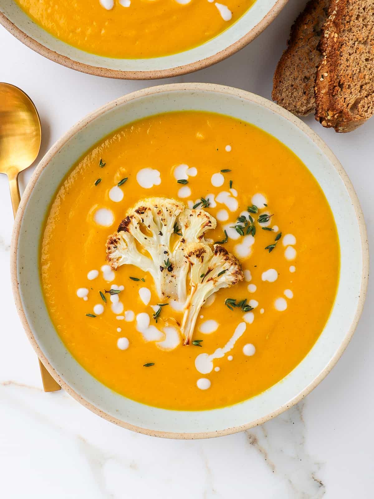 Pumpkin soup served in a bowl with roasted cauliflower on top.