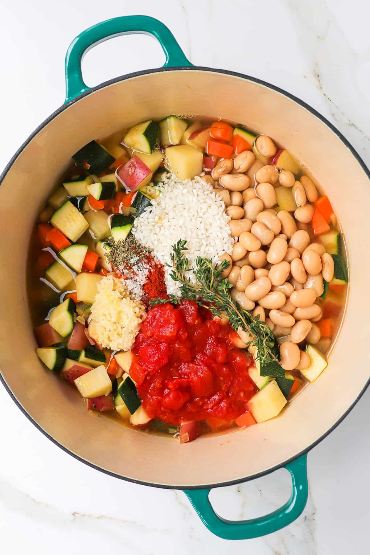 Stew ingredients in a pot with raw rice on top.