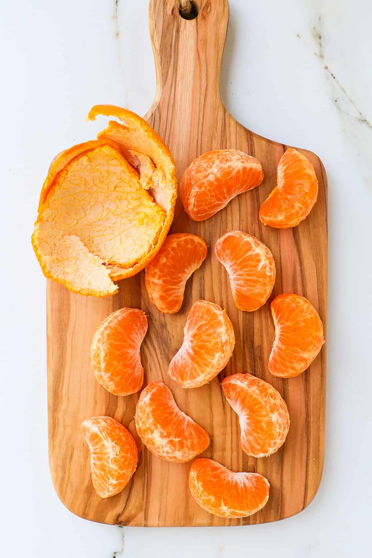 Mandarin orange segments on a wooden cutting board.