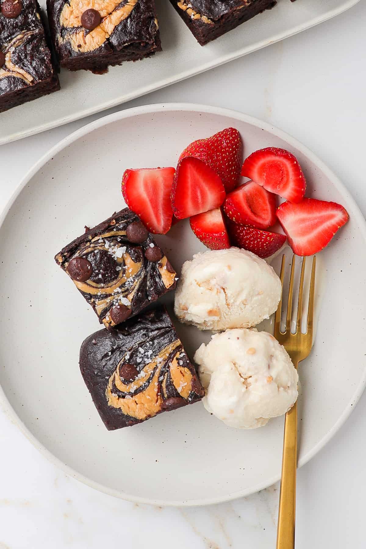 Brownies on a plate with ice cream and strawberries.