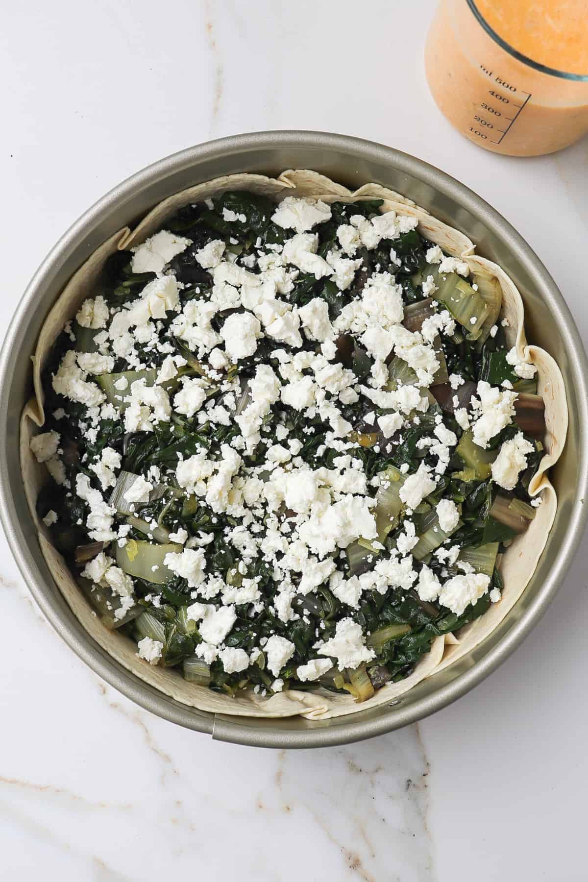 Cooked silverbeet and feta in tortilla curst before egg mixture poured on top.