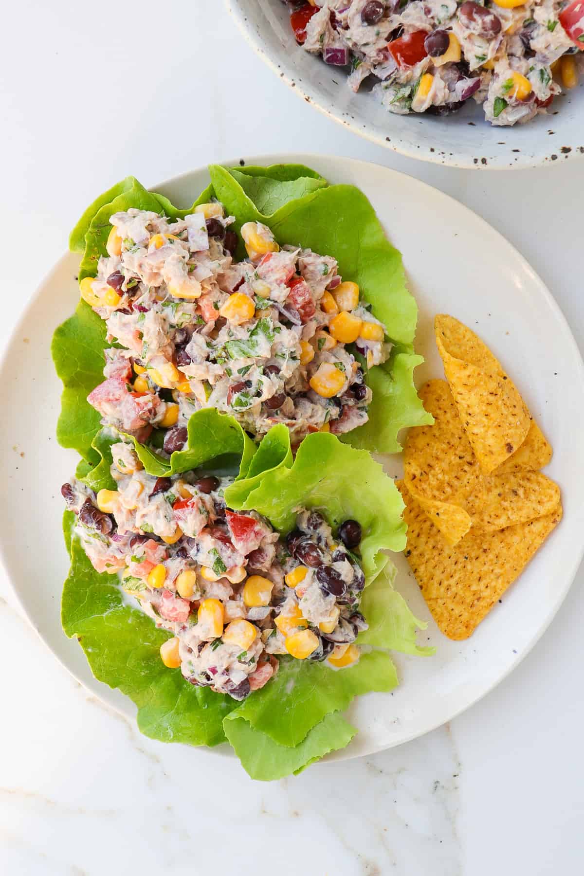 Mexican tuna salad lettuce wraps pn a plate served with corn chips.