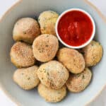 Potato croquettes in a bowl with marinara sauce.