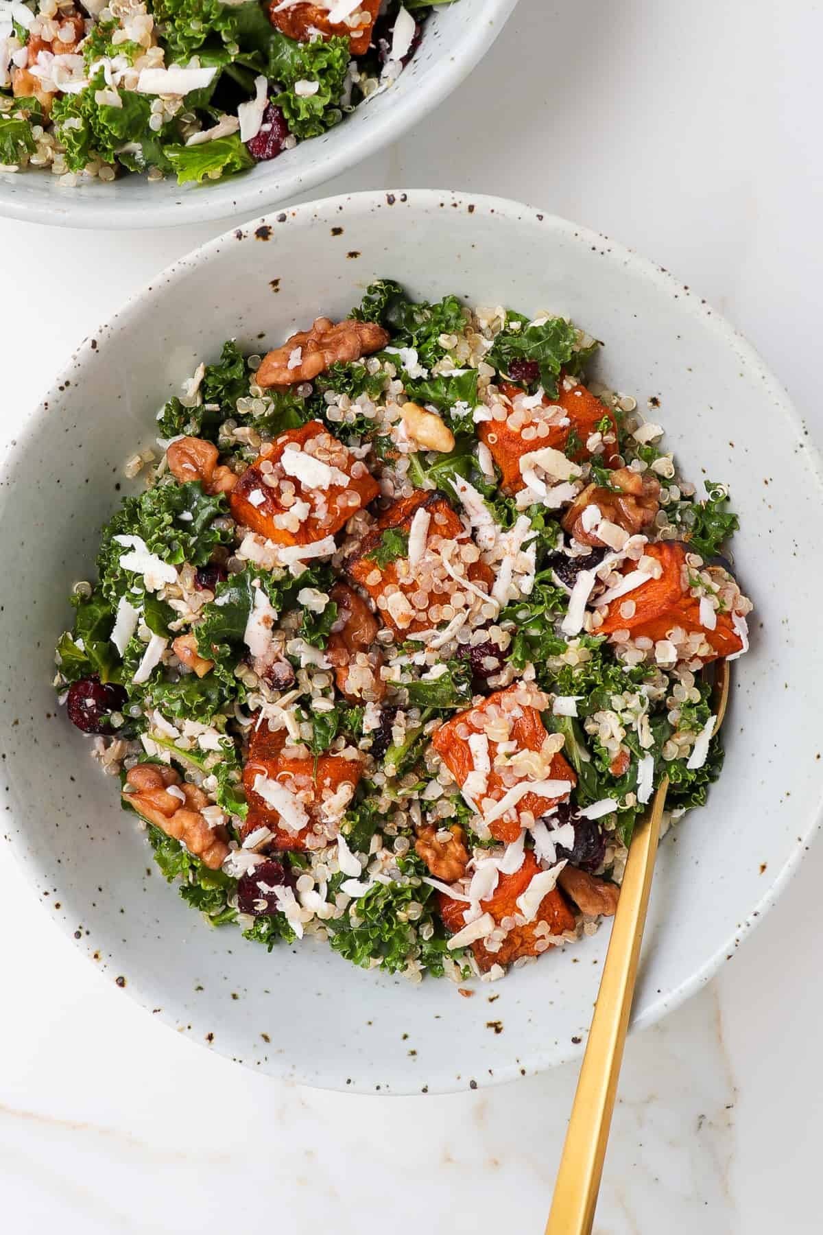 Pumpkin quinoa salad in a bowl with gold fork.