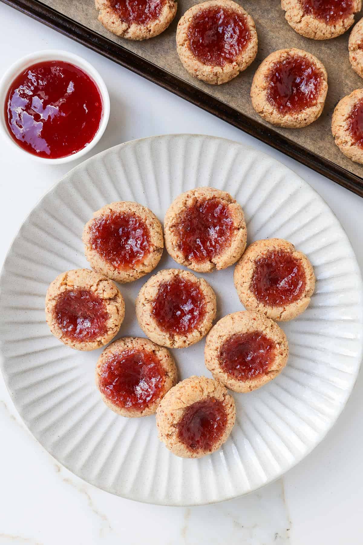 Strawberry jam thumbprint cookies on a plate.