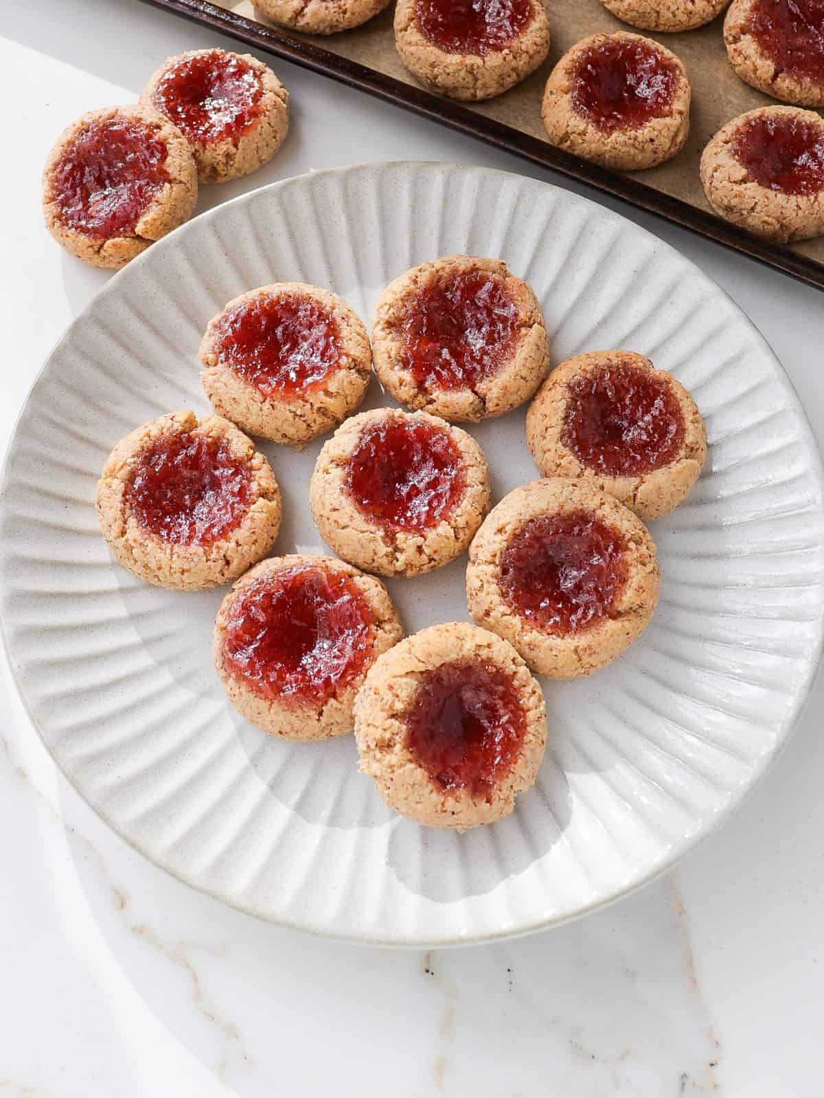 Side shot of strawberry jam thumbprint cookies on a plate.