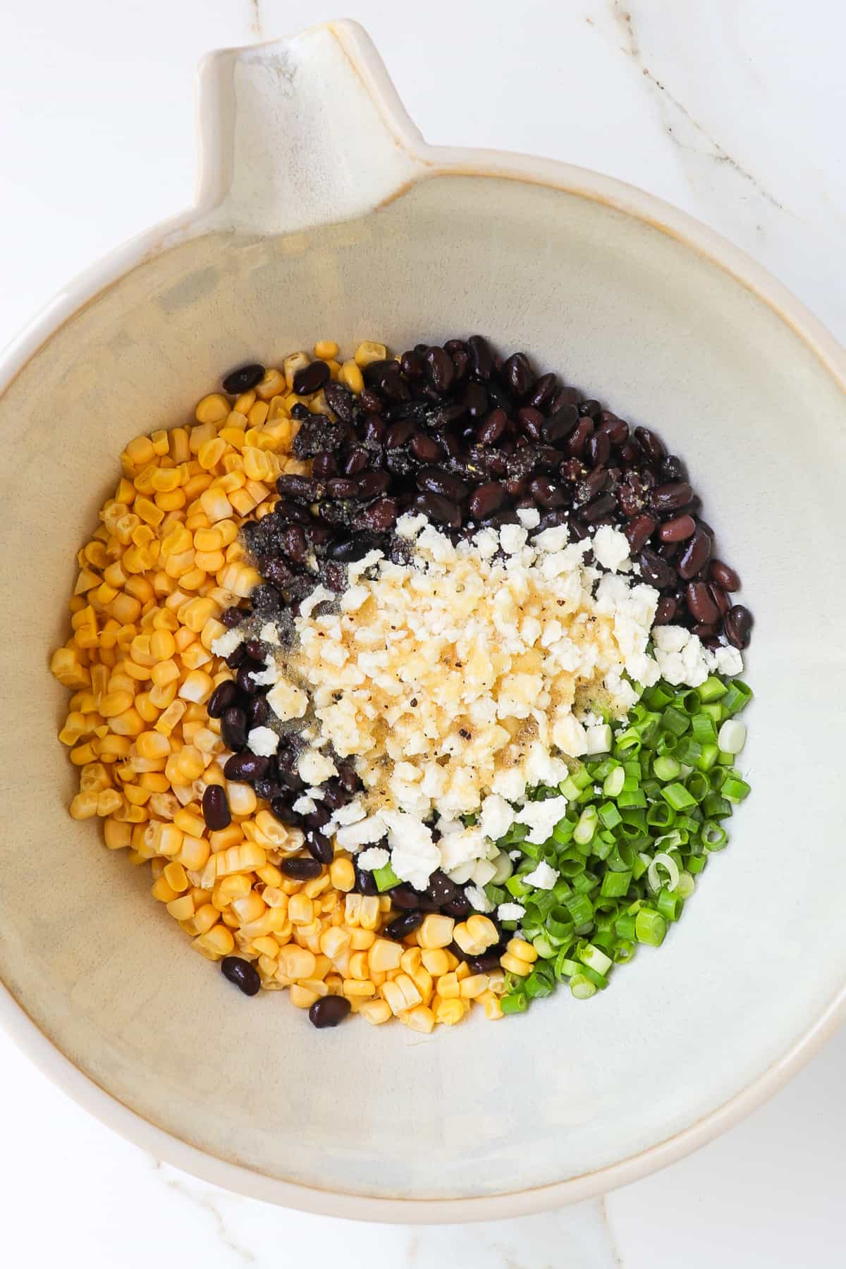 Fresh corn, black beans, crumbled feta cheese, spring onions and dressing in a large mixing bowl.