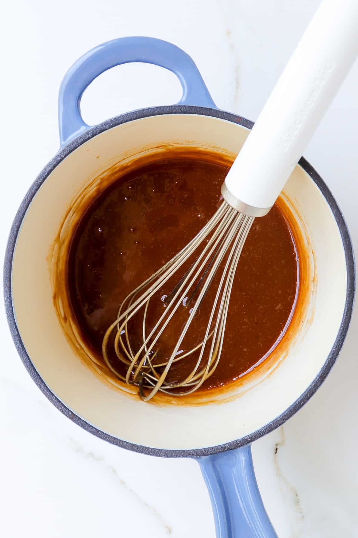 Teriyaki Sauce in a saucepan with a white whisk.