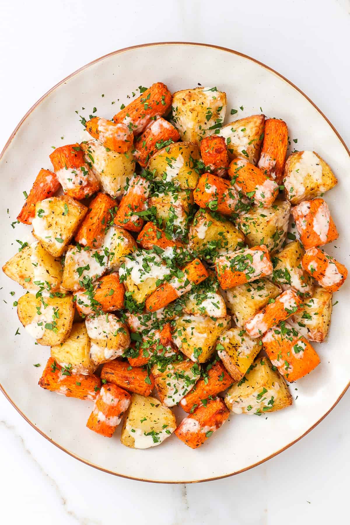Air fryer carrots and potatoes with tahini and herbs on top.