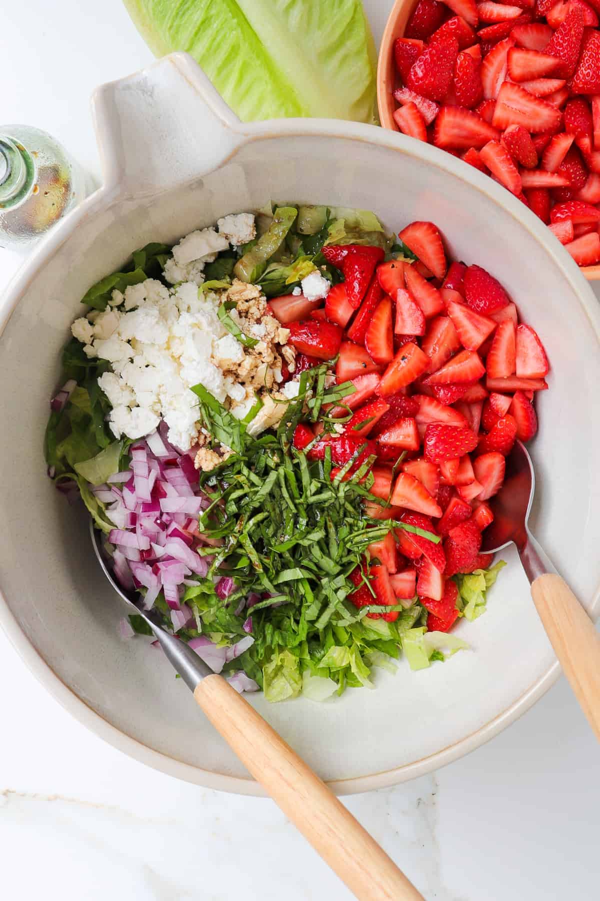 All of the salad ingredients in a large mixing bowl, unmixed.