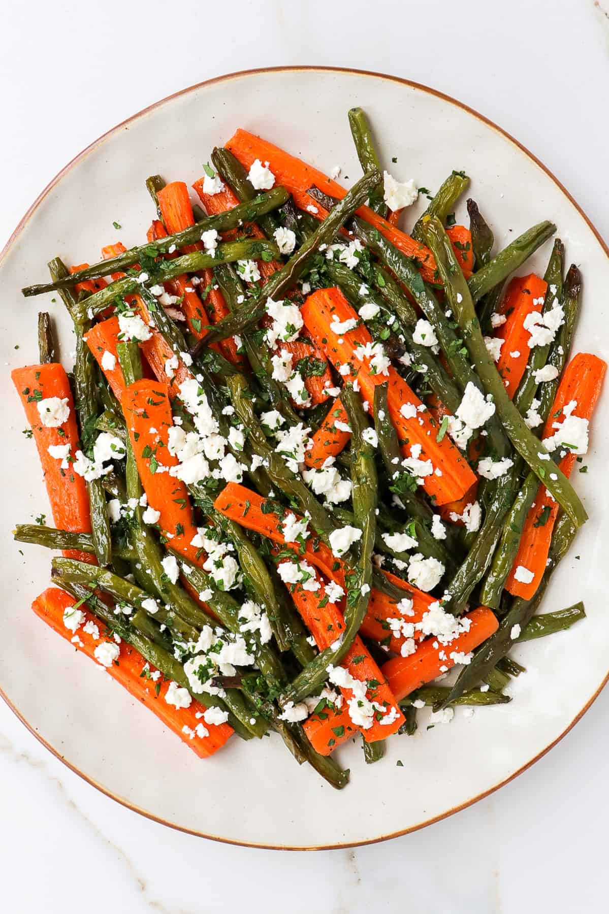 Roasted carrots and green beans with feta on a plate.