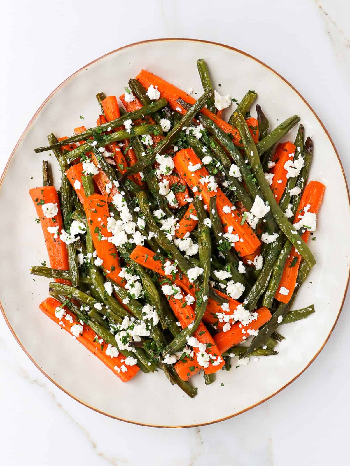 Roasted carrots and green beans with feta on a plate.