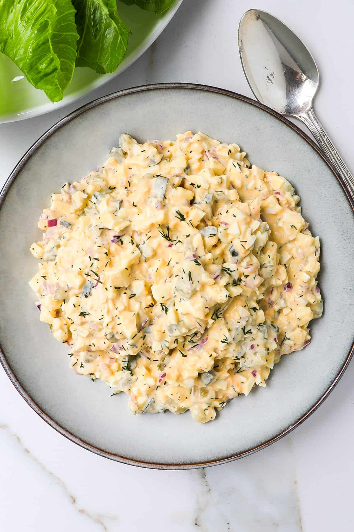Egg salad in a bowl with silver spoon on the side.