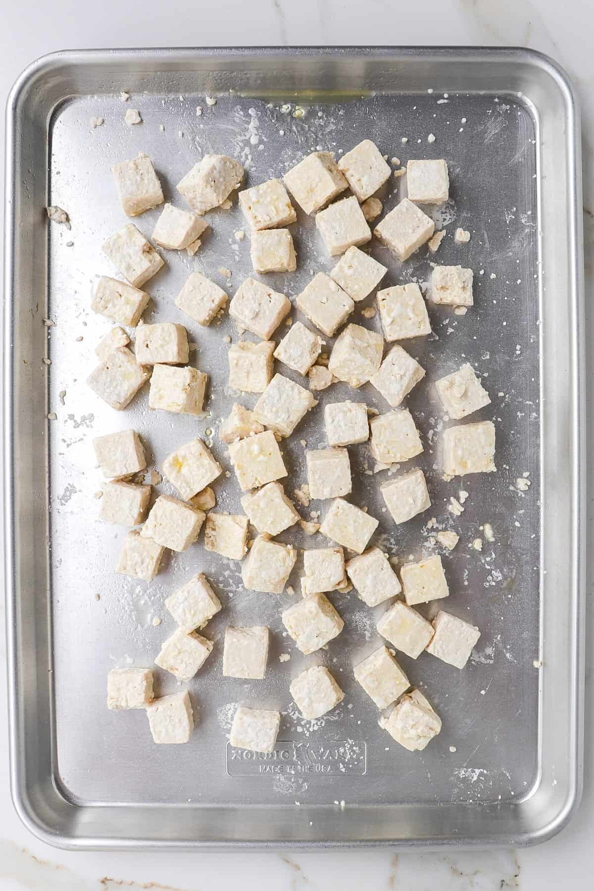 Tofu cubes coated in tapioca flour on baking tray.