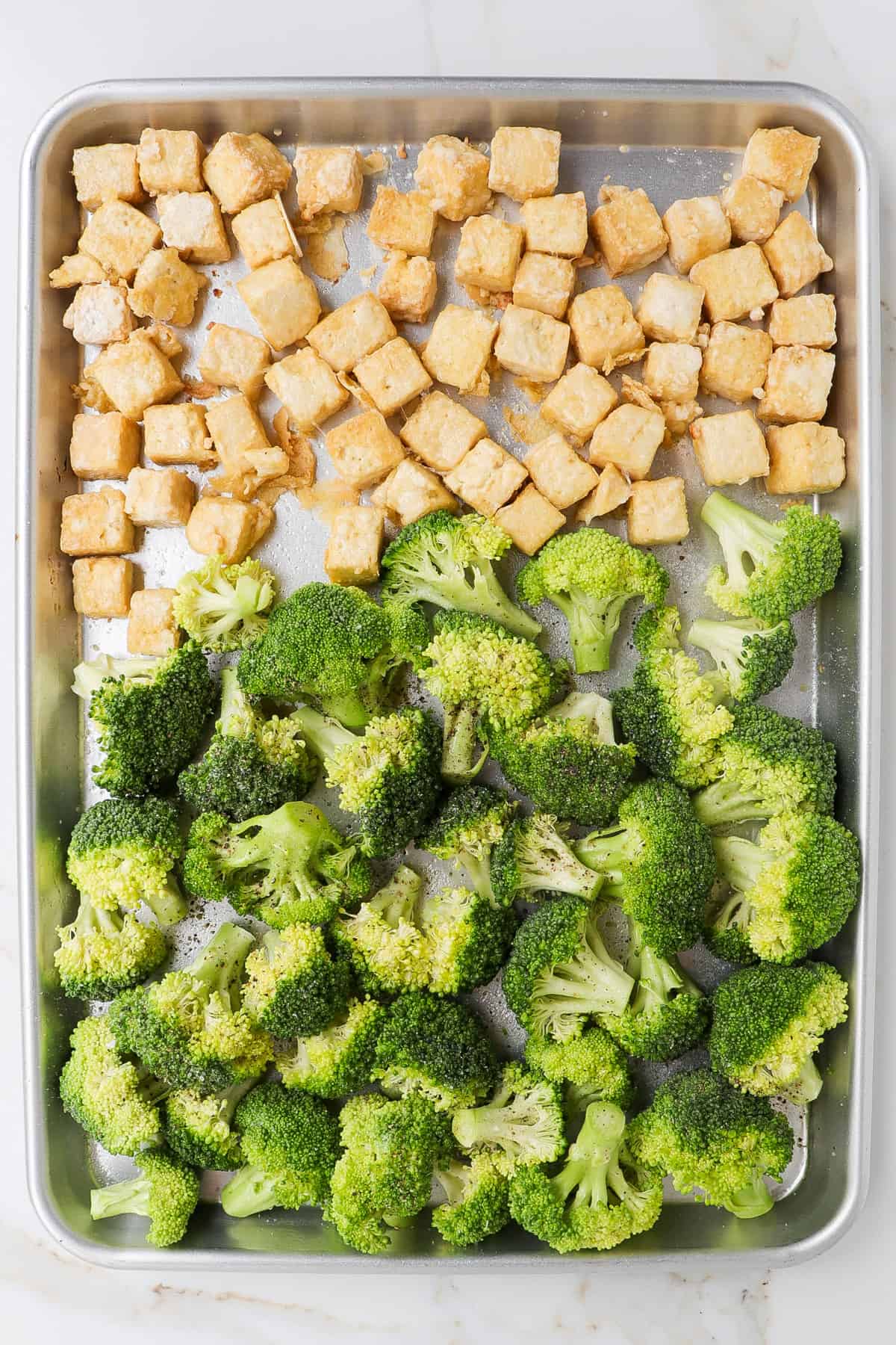 Baked tofu and seasoned broccoli on a pan.