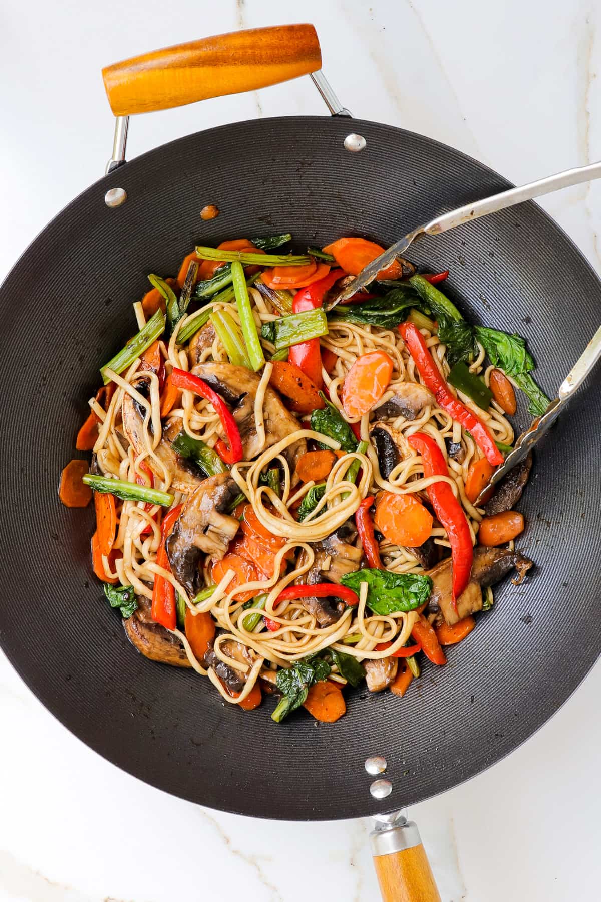 Vegetables and udon noodles in a wok.