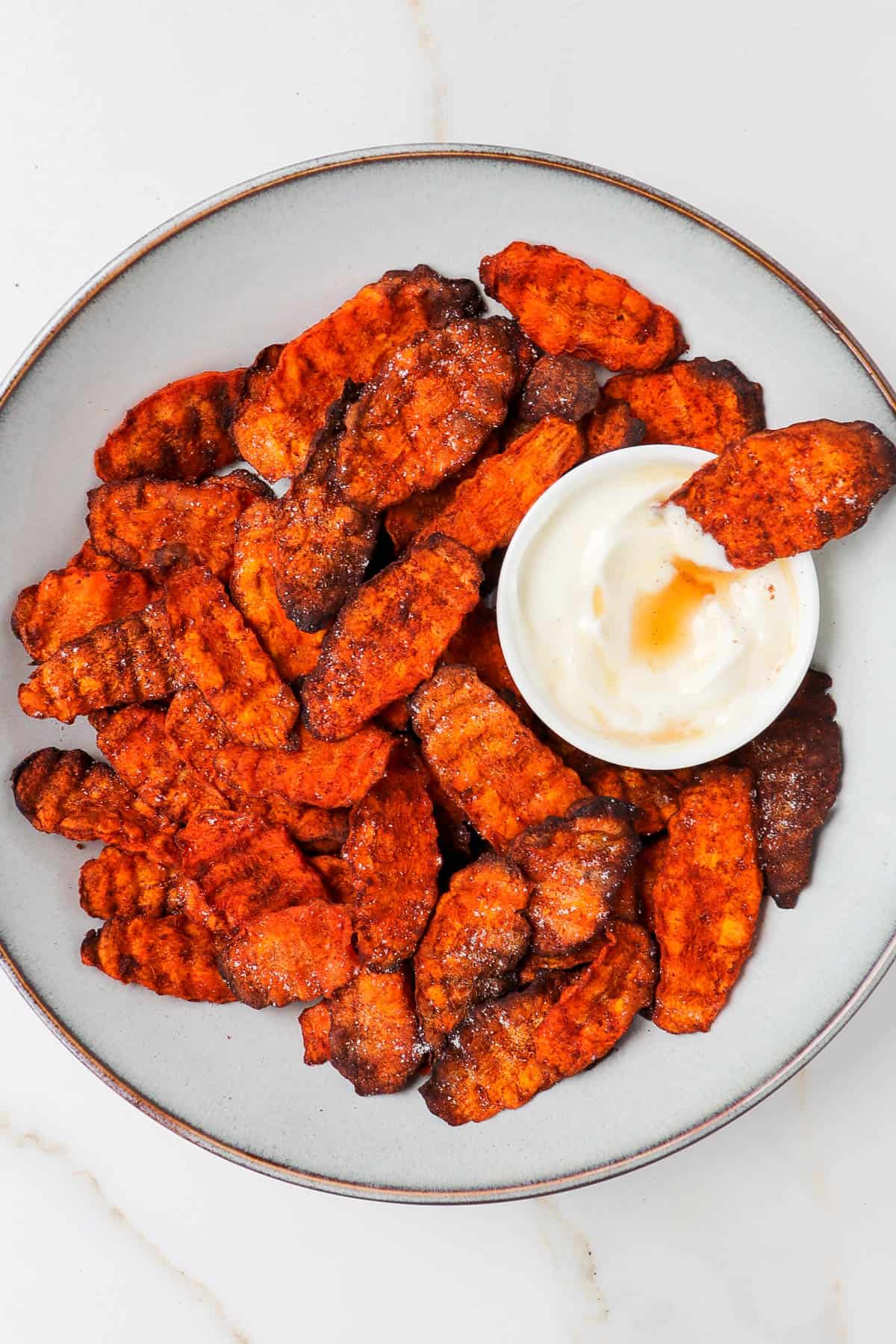 Air fryer carrot chips in a bowl dipped in yoghurt.