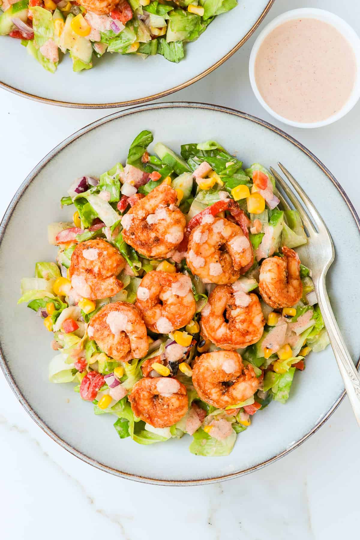 Cajun shrimp salad served in a bowl with extra dressing.