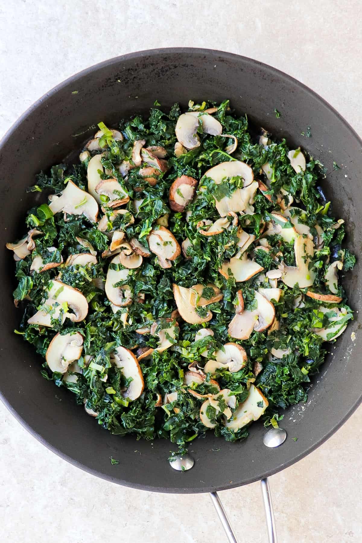 Kale and mushroom mixture in a frying pan.