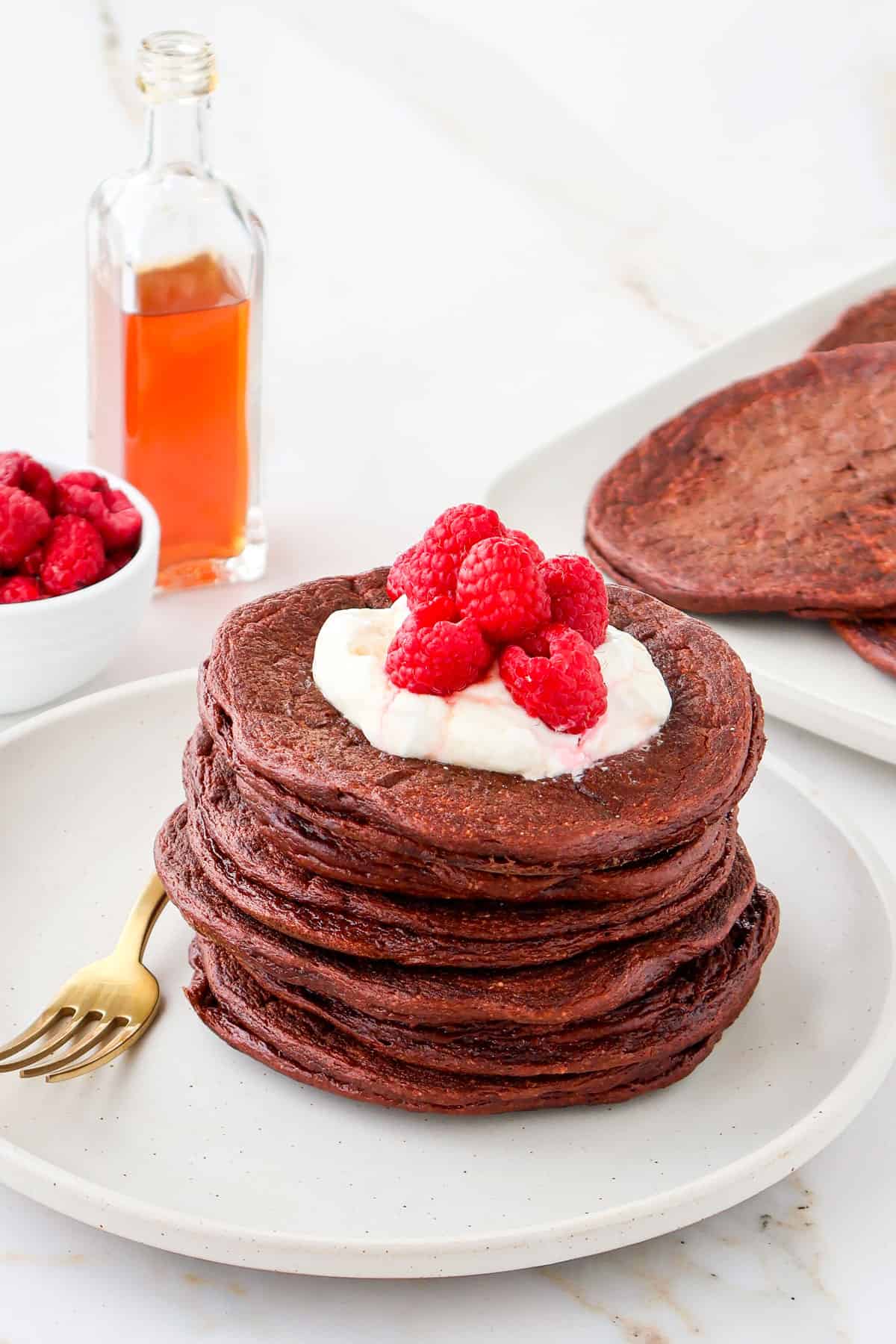 Side shot of chocolate protein pancakes with a gold fork on the side.