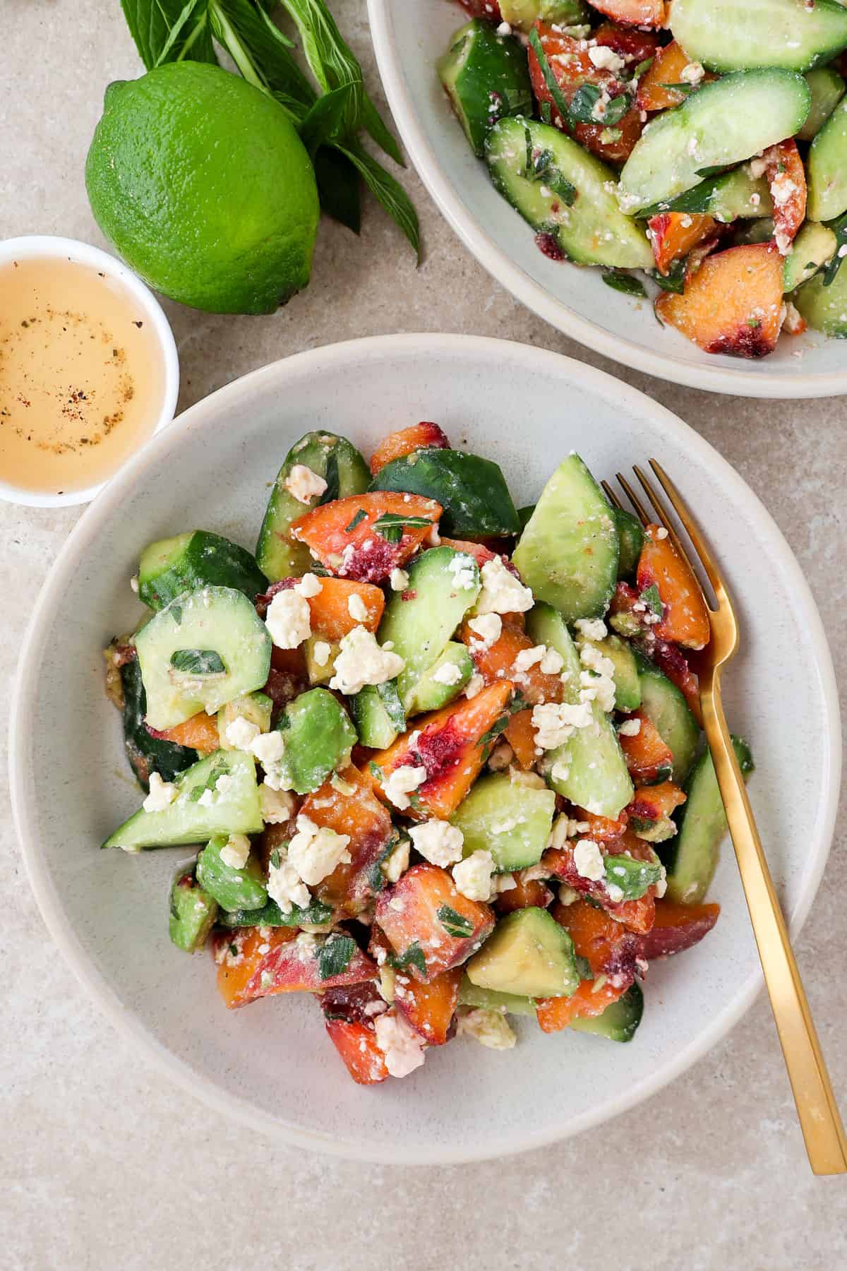 Cucumber peach salad in bowls with a fork.
