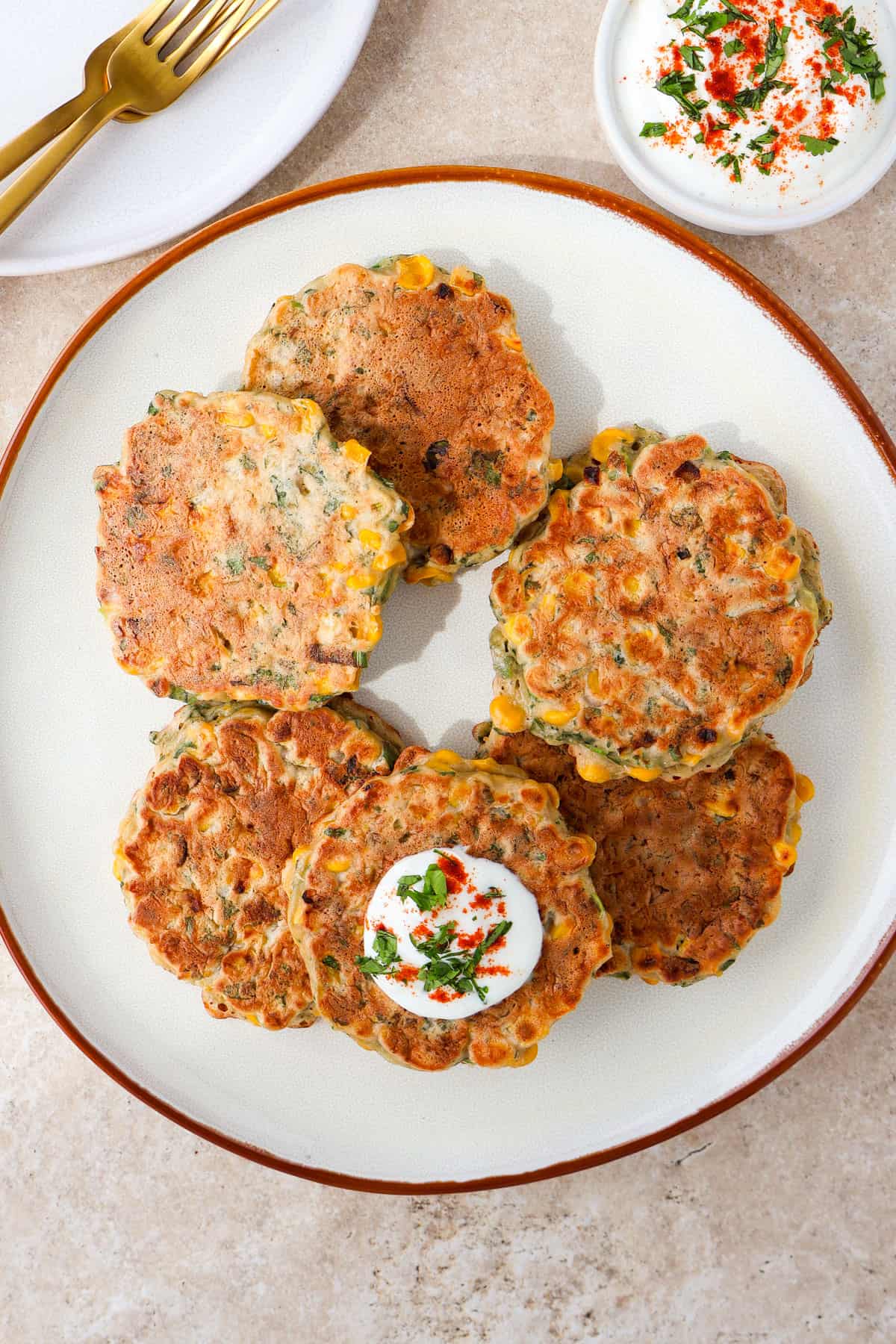 Fritters on a plate. One topped with paprika yogurt.